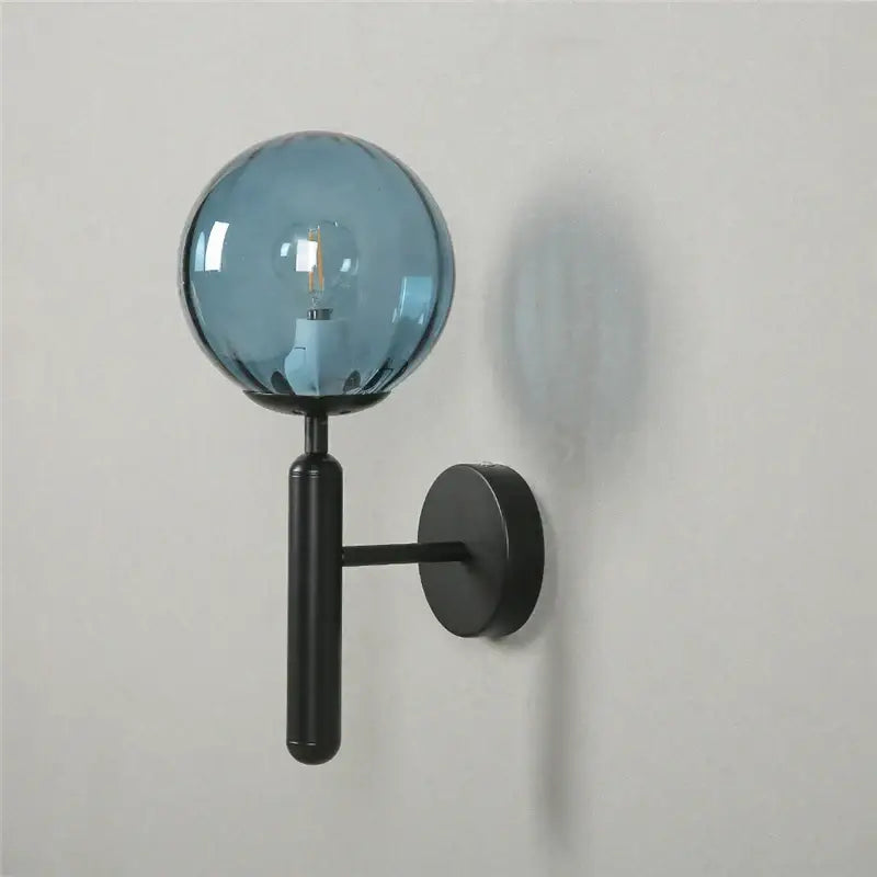 Modern brass and pink glass wall sconce with decorbites blue glass globe and black metal arm for bedroom lighting decor