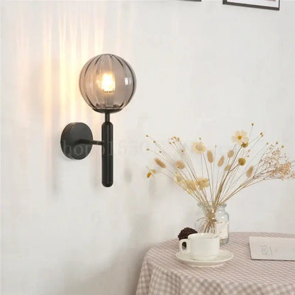 Modern black wall sconce with a smoked glass globe featuring brass accents for elegant bedroom decorbites blue glass use