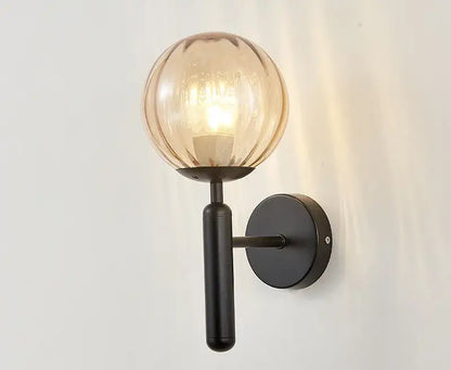 Modern black metal wall sconce with warm amber glass globe contrasting decorbites blue glass balls for bedroom lighting