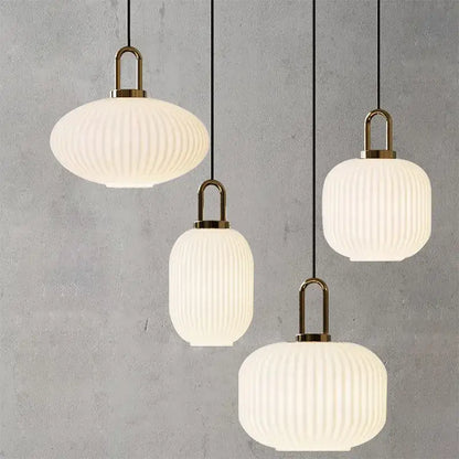 Four modern brass pendant lights with frosted white striped glass shades for dining room lighting