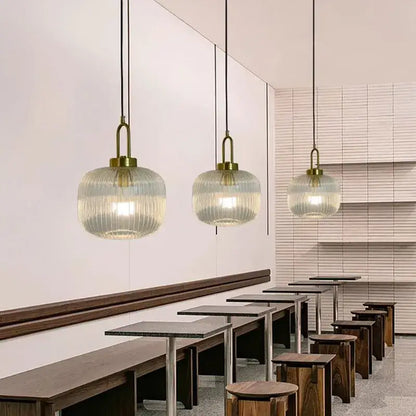 Three elegant brass finish pendant lights with ribbed striped glass globes for modern dining room lighting