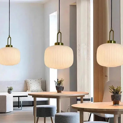 Three elegant modern brass pendant lights with warm striped glass shades for dining room use