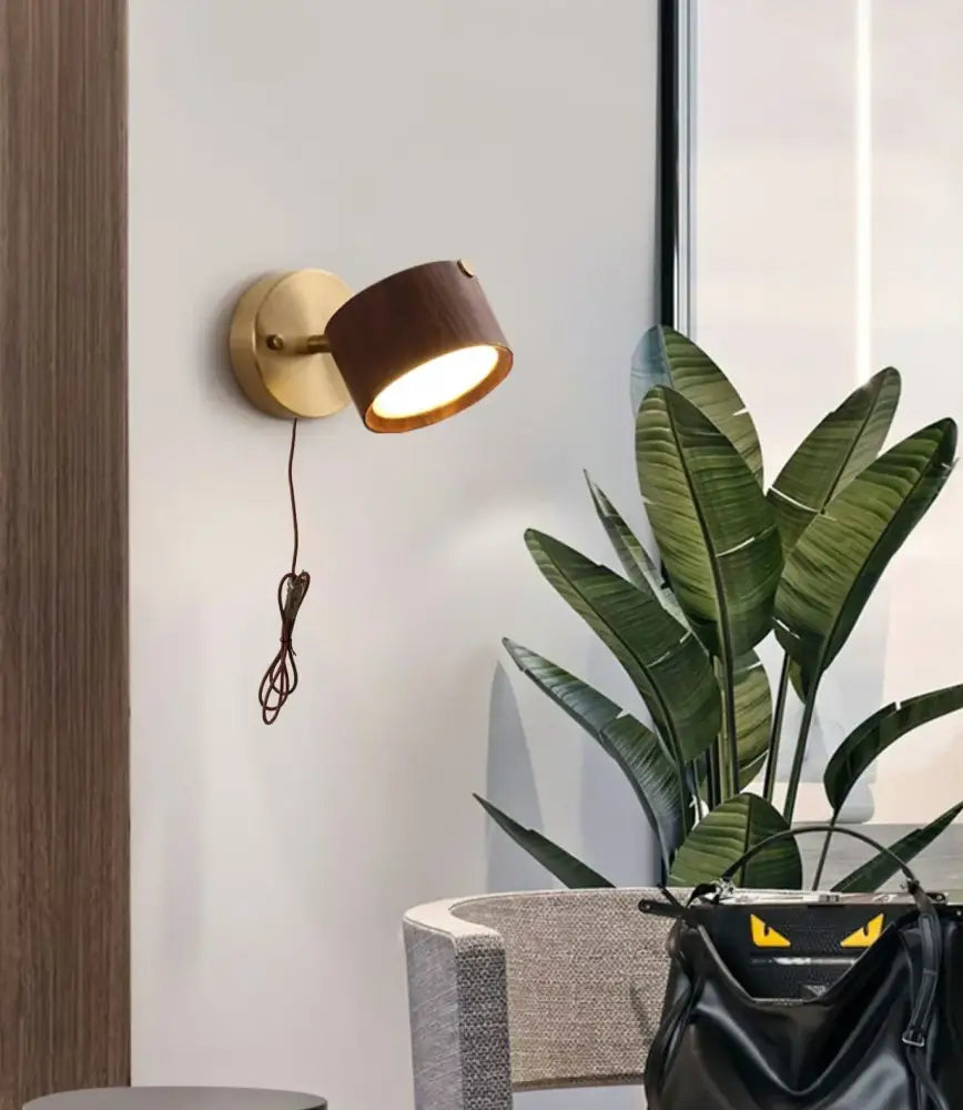Modern brass and walnut led wall sconce with brass circular base and dark wood textured shade for bedroom spotlight