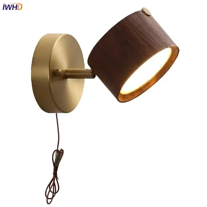 A warm-toned modern brass and walnut led wall sconce with a cylindrical wooden shade for bedroom spotlighting