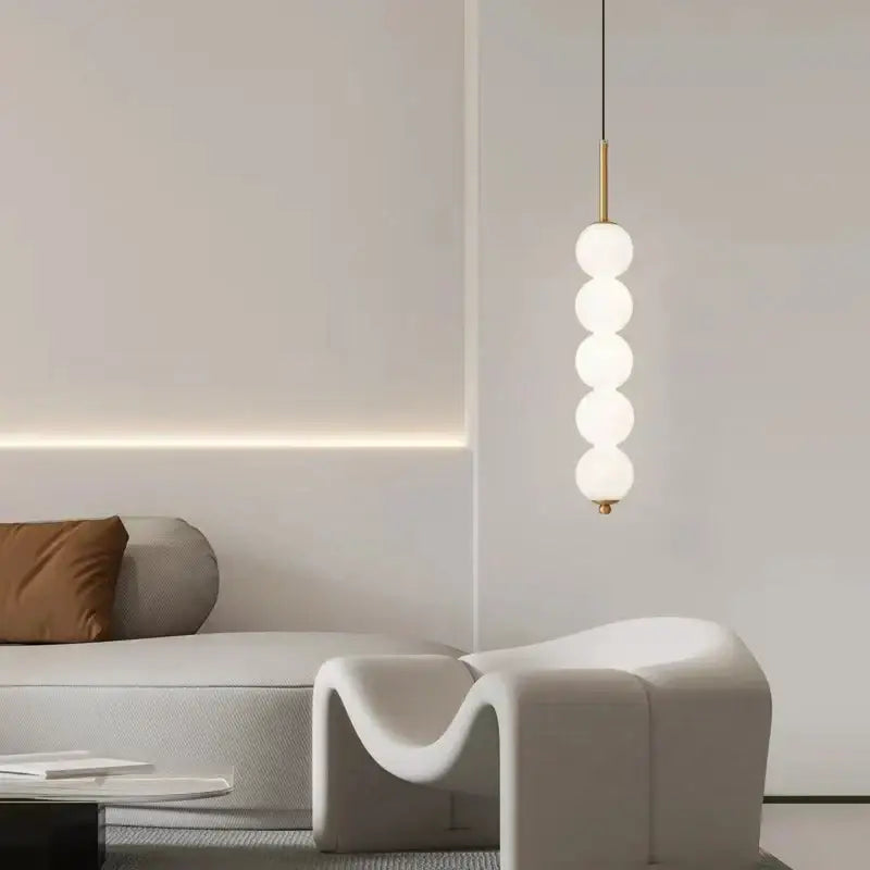 A modern brass and white pearl led pendant light with five frosted glass spheres for kitchen decorbites led white lighting