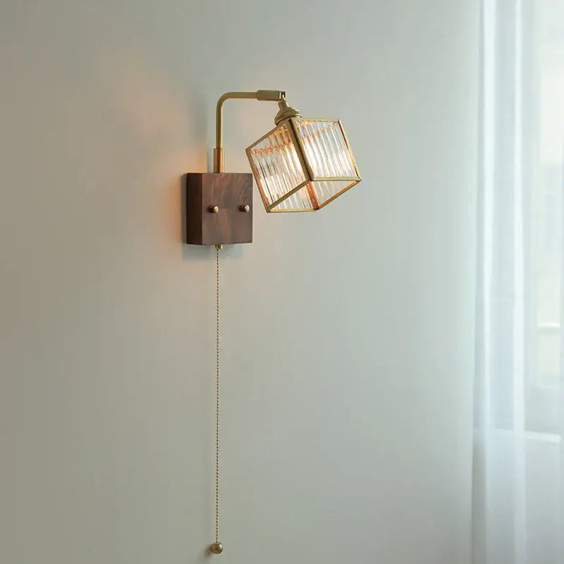 Modern brass and wood led wall light with geometric blue glass cube shade, adjustable arm, and pull-chain switch for bedroom