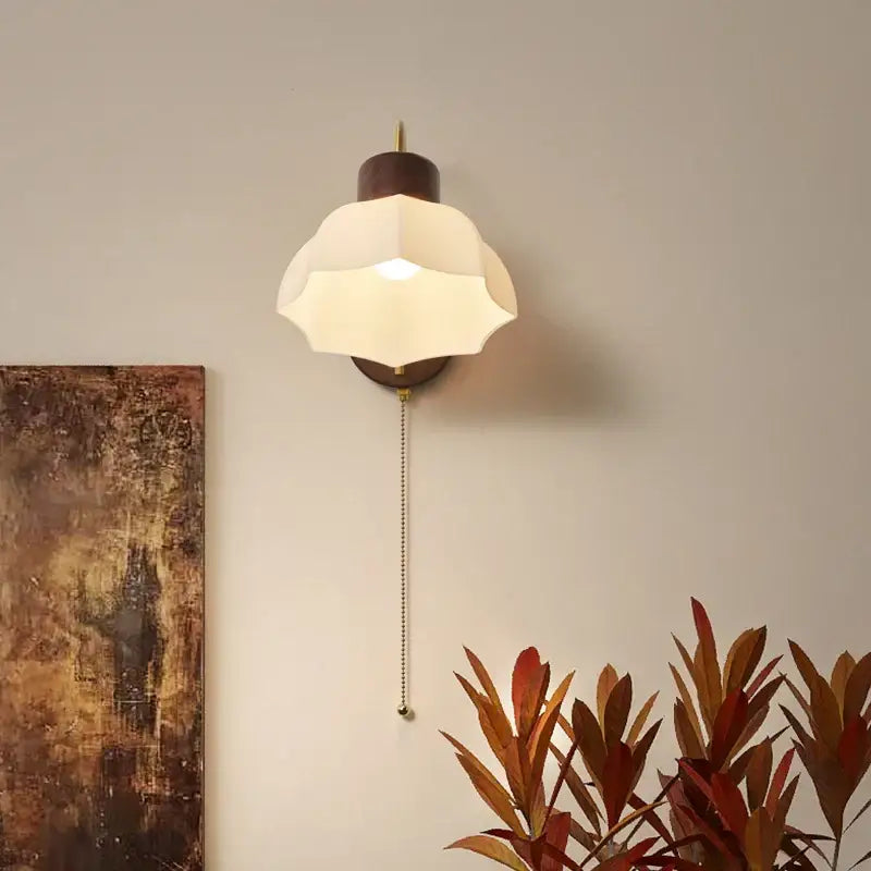 Modern brass and wood led wall sconce with a warm-toned petal-shaped frosted glass shade and wall sconce pull chain