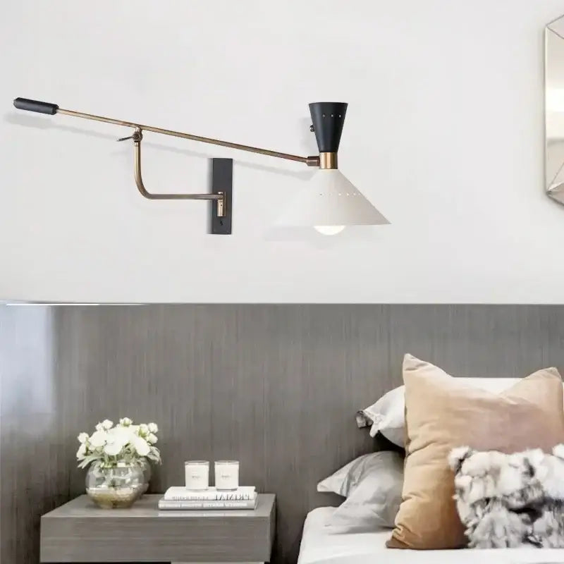 A sleek black and brass decorbites adjustable metal bedroom sconce with white conical shade for modern bedroom decor