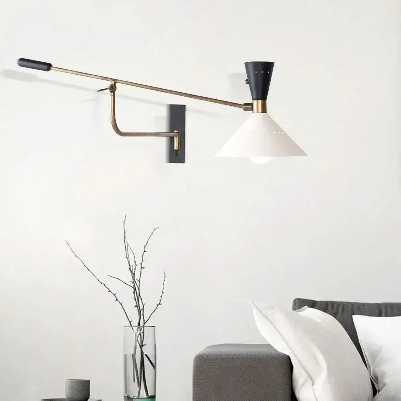 A sleek black and brass decorbites adjustable metal bedroom sconce with a white conical shade for modern decor