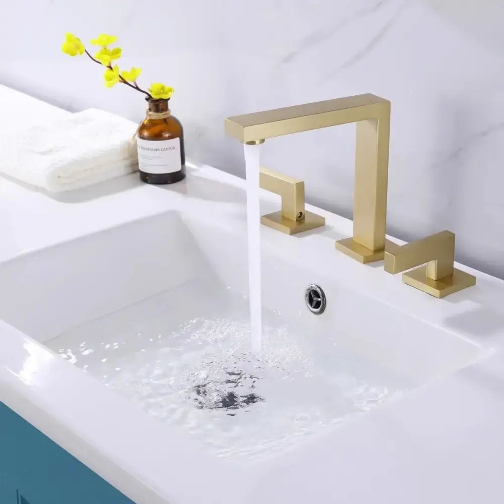 Modern brass black basin faucet with gold-toned rectangular spout and three square handles on white sink decorbites brass black