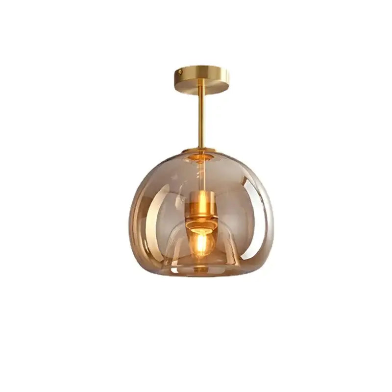Modern brass and black glass ball led ceiling light with translucent amber glass globe featuring polished brass hardware