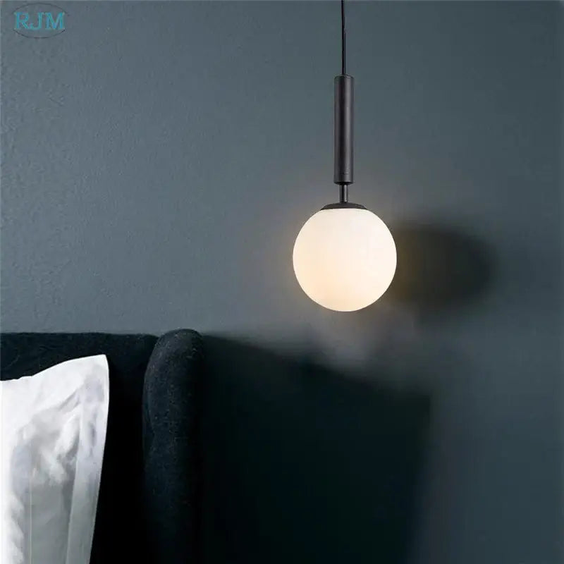 Black cylindrical pendant light featuring a frosted glass globe in modern brass and black glass ball led decorbites design