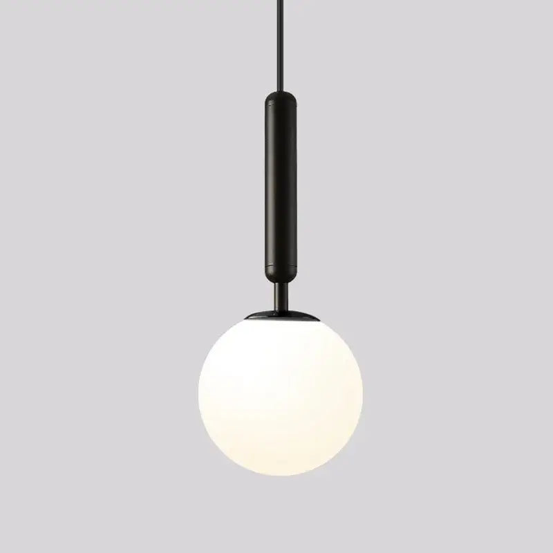 Modern brass and black glass ball pendant light featuring a black cylindrical fixture with frosted white globe for dining room decorbites glass ball pendant
