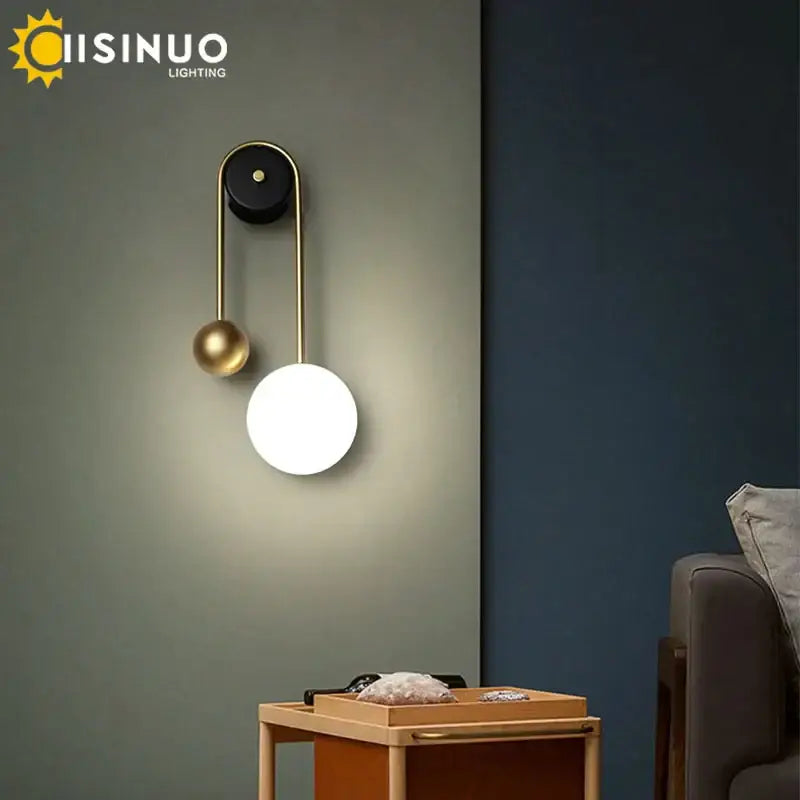 Modern brass and black led wall sconce with spherical white light fixture and smaller gold sphere accent for living room decor