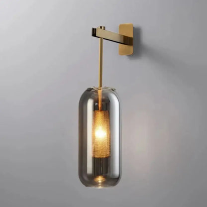 Modern brass and black wall sconce lights with a sleek brass arm and cylindrical smoked glass shade for bedroom use