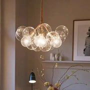 Modern brass bubble chandelier featuring glass bubbles brass-toned metal arms and woven cord suspension by decorbites bubble chandelier