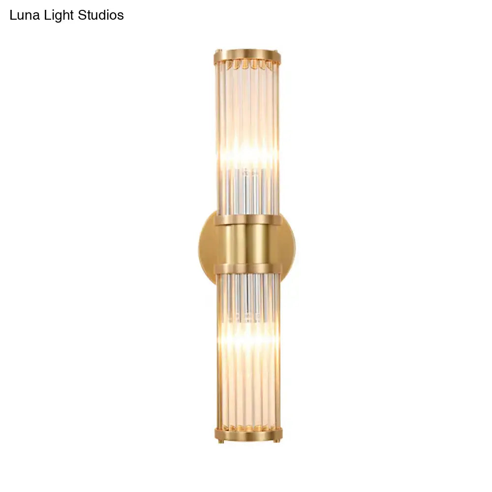 Modern brass clear crystal wall lamp with gold-toned vertical glass tubes and circular mounting plate for bedroom sconce