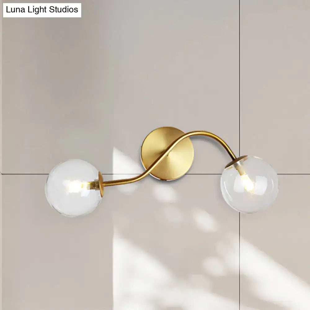 Brass-finished wall lamp with two clear tan glass globes and bulb base designed for modern stairway lighting