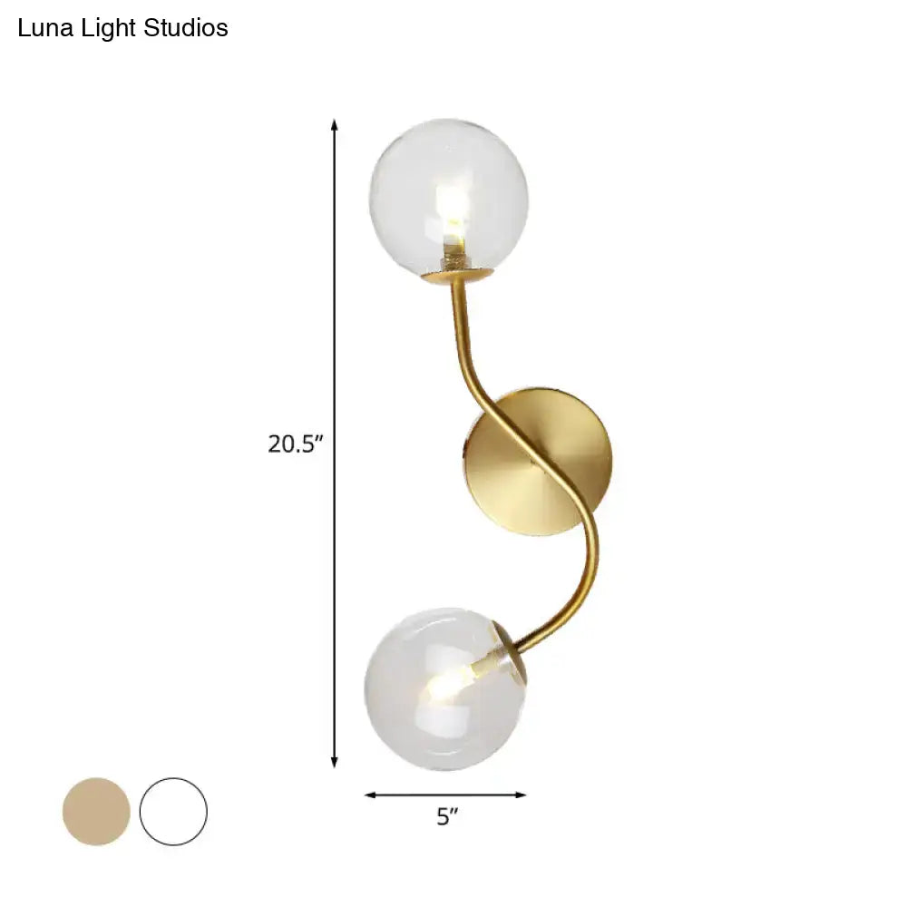 Modern brass clear tan glass wall lamp with gold-toned twisted metal arm and two clear glass globe shades bulb base