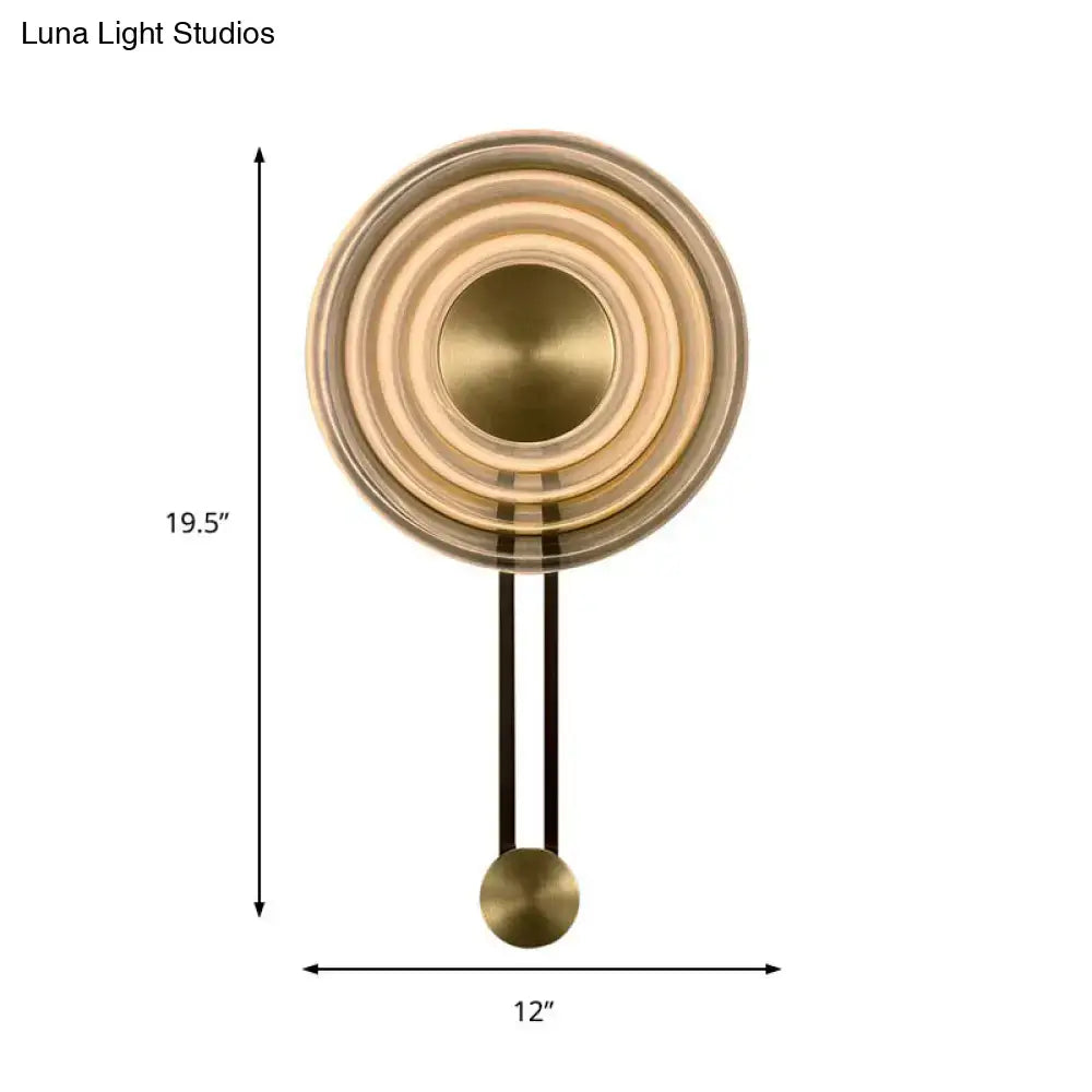 Modern brass concentric circle wall lamp with sleek design and black hanging rod highlighting fixture height for living room