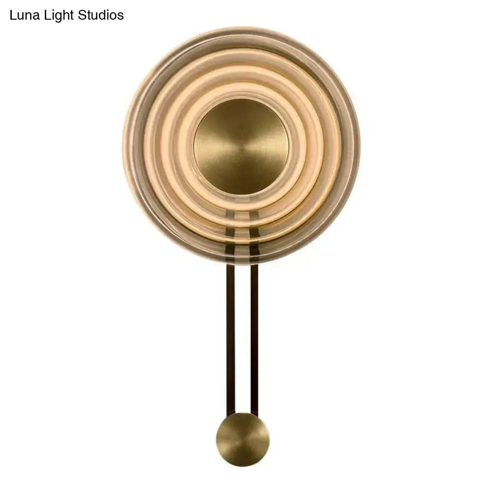 Modern brass concentric circle wall lamp with polished metallic finish and spherical pendulum showcasing fixture height