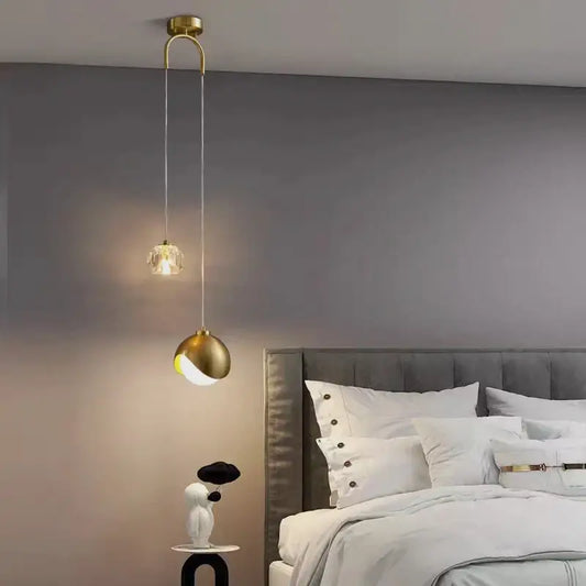 A modern brass crystal ball pendant light with a crystal-encrusted bulb and sleek curved design for bedroom decorbites decor