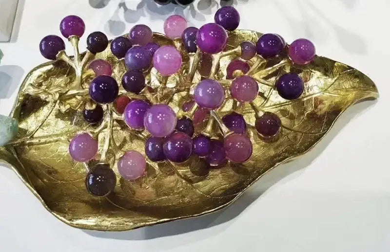 A modern brass crystal grape ornament features polished purple and pink agate beads on a golden leaf tray