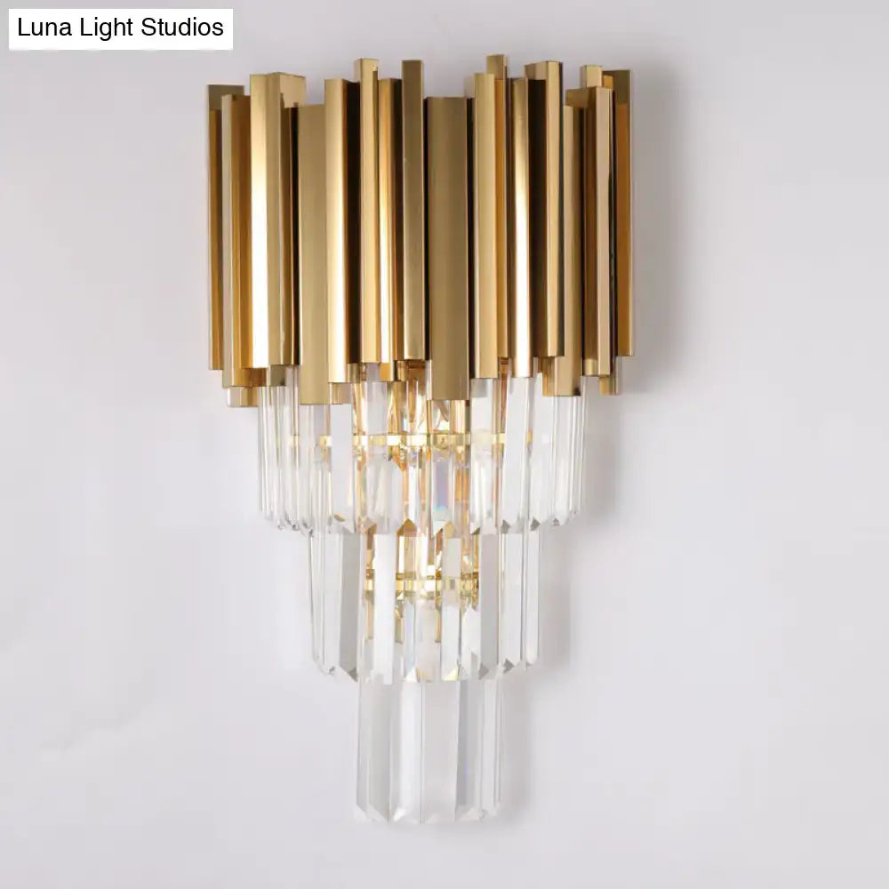 Modern brass wall lamp with gold-toned finish and cascading crystal prisms direct wired electric for living room use