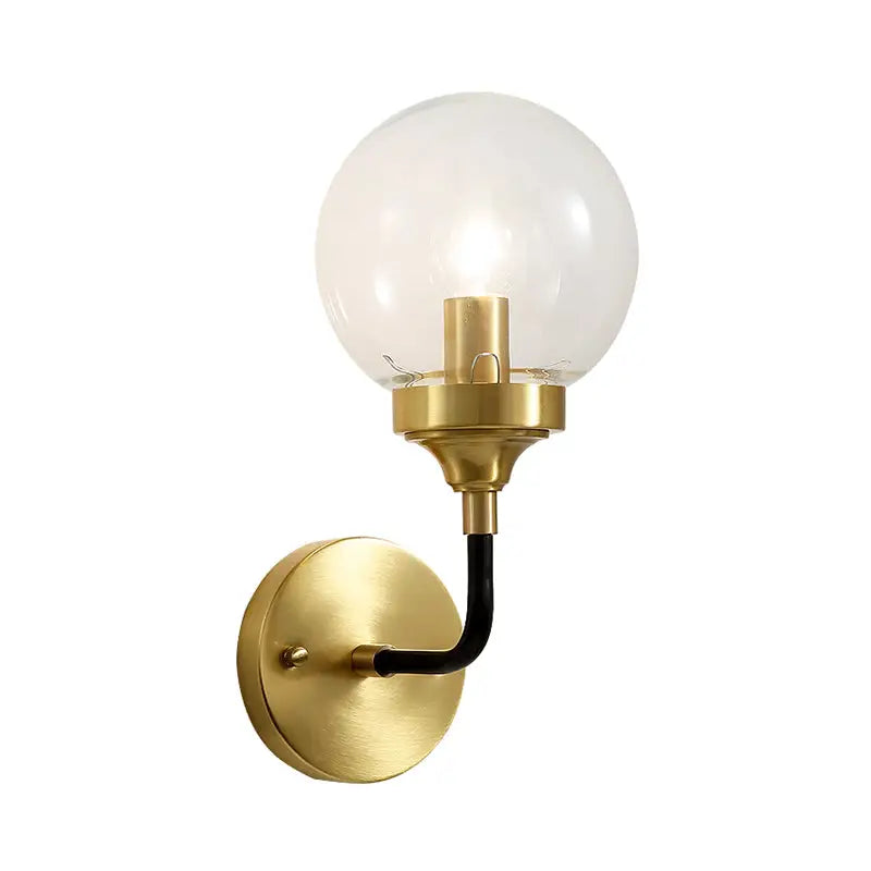 Modern brass curved arm wall sconce with clear glass globe and gold-toned finish for bedroom lighting