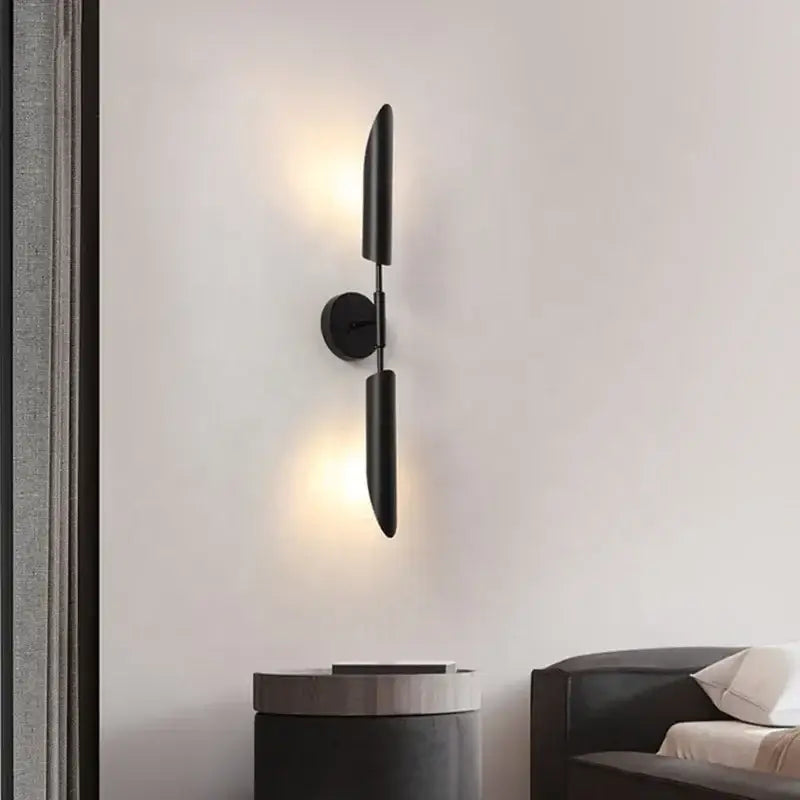 Modern brass cylindrical wall light featuring black minimalist vertical arms and circular base for golden luxury wall decorbites wall light