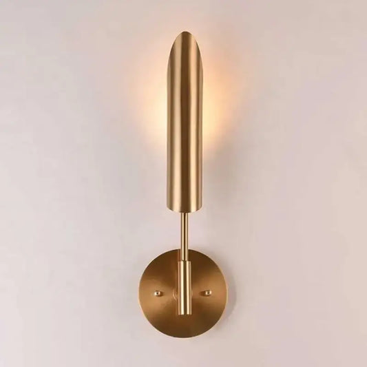Modern brass cylindrical wall light with a sleek elongated shade and circular base for decorbites golden luxury decor