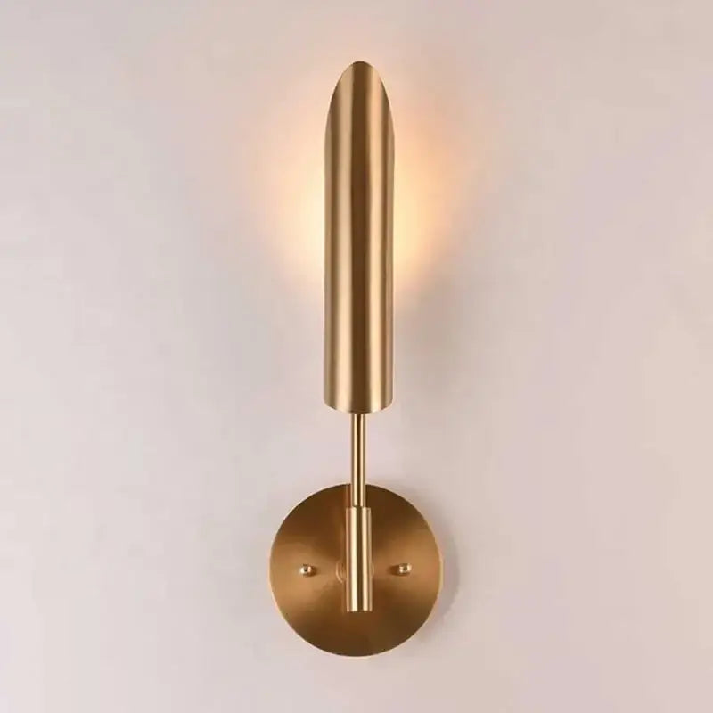 Modern brass cylindrical wall light with a sleek elongated shade and circular base for decorbites golden luxury decor