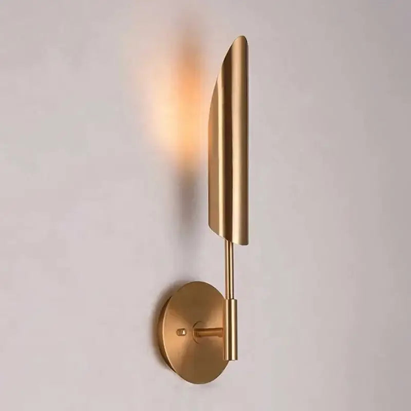 Modern brass cylindrical wall light with gold-toned leaf-shaped shade showcasing decorbites golden luxury wall design