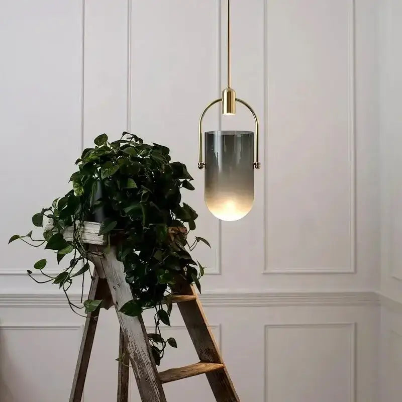 A modern decorbites bucket chandelier with brass metal frame and gradient gray glass shade for dining room lighting