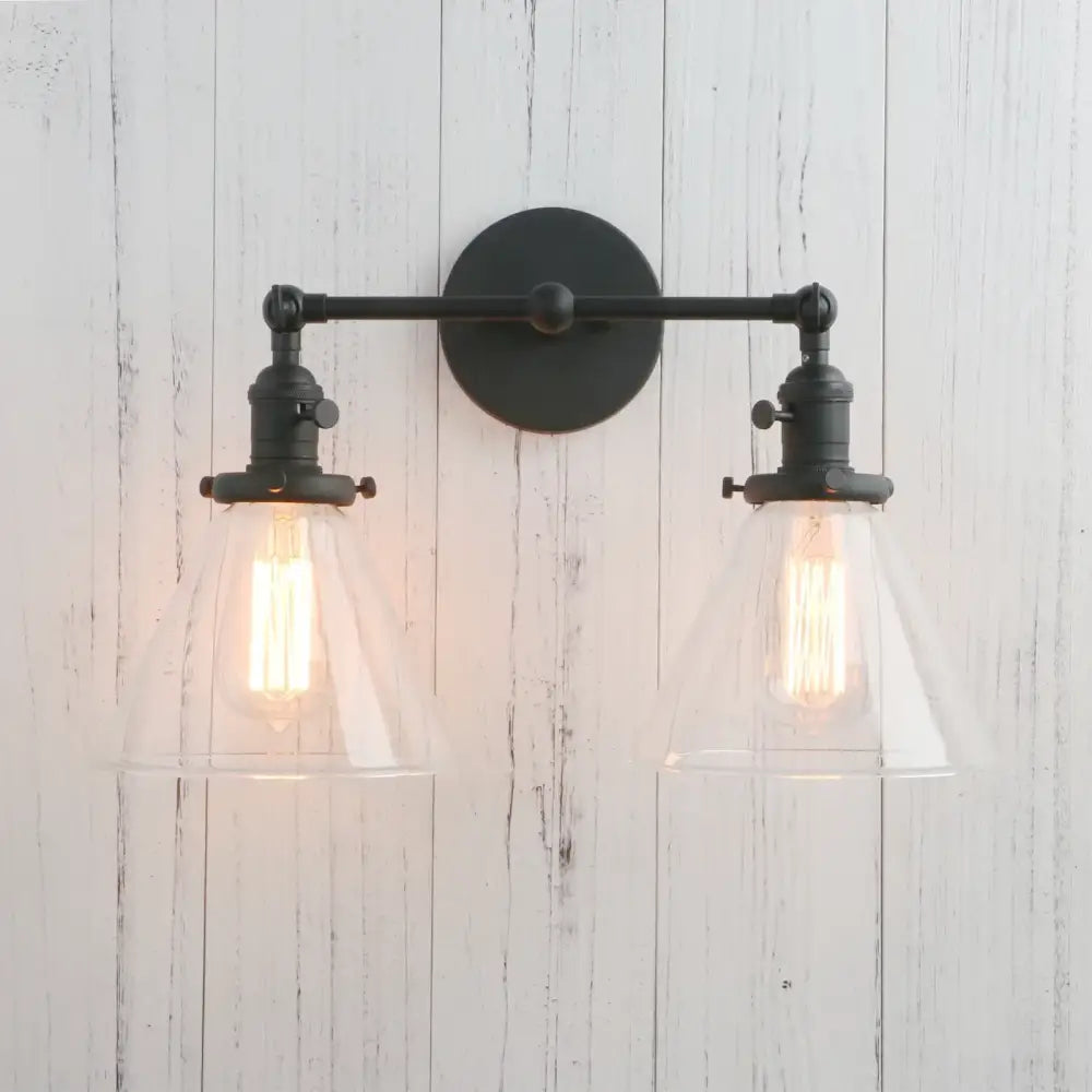 Black wrought iron wall sconce with two clear decorbites funnel glass shades and exposed filament bulbs light fixture