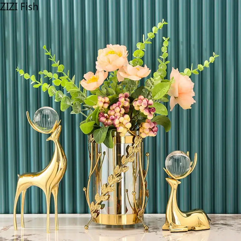Gold metallic vase with leafy design and clear glass accents holding peach flowers as part of brass deer statue desk ornament decorbites brass deer living room decor
