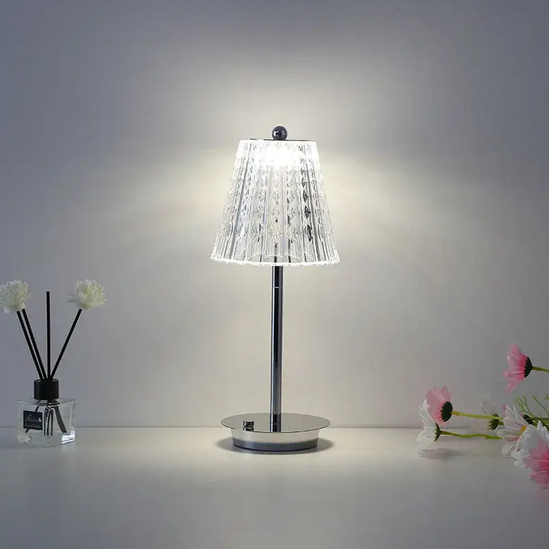 A modern brass diamond touch desk lamp with a clear faceted glass shade and polished chrome base for bedroom use
