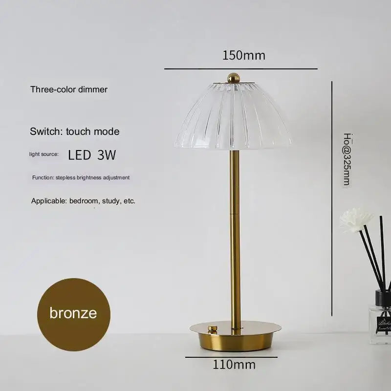 A modern brass diamond touch desk lamp with a sleek bronze finish and clear fluted glass shade featuring touch controls