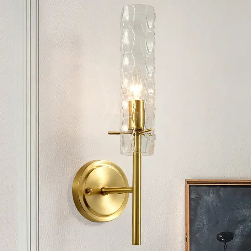 Modern brass dimpled blown glass wall light featuring a gold-toned sconce with a textured blown glass cylinder and brass finish