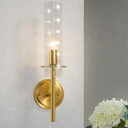 Modern brass wall light with gold-toned dimpled blown glass cylinder diffuser for bedroom sconce lighting