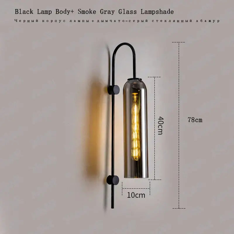 Black metal wall light with a tall cylindrical smoke gray e27 glass wall light lampshade housing an exposed bulb
