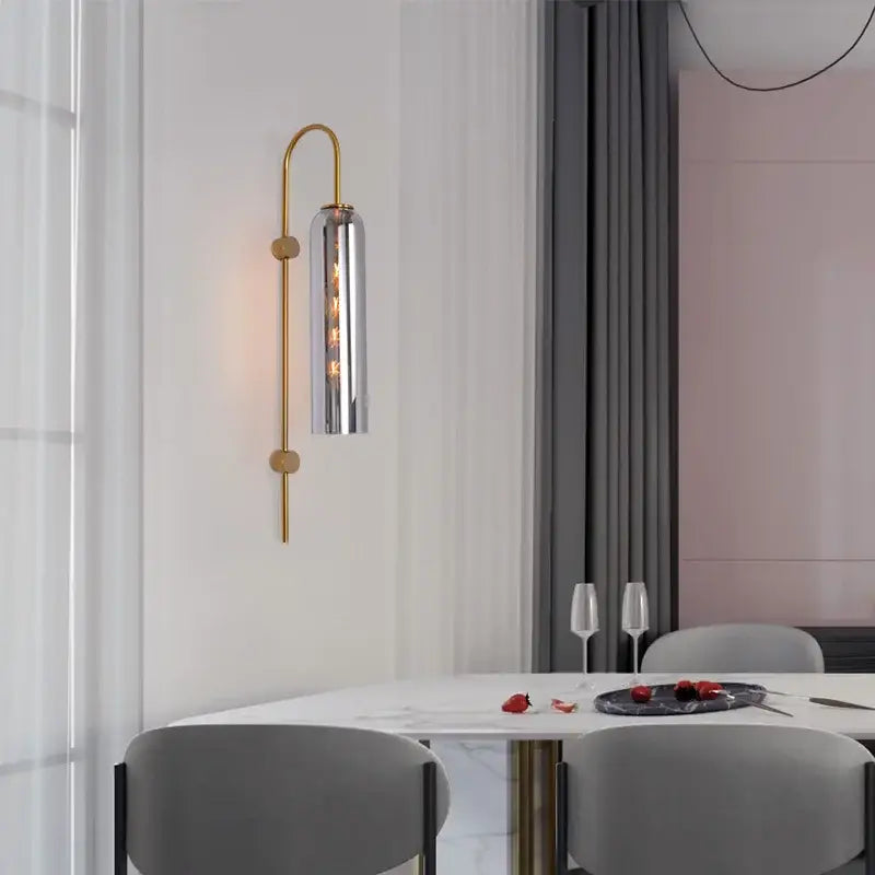 Modern brass e27 glass wall light with gold-toned curved arm and cylindrical shade for bedroom wall light use