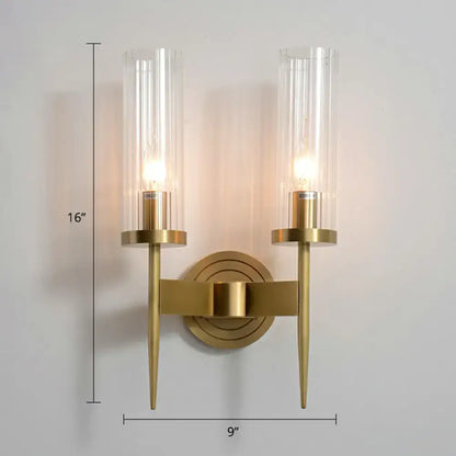 Modern brass finish wall light with gold-toned metal arms and two clear glass tube cylinders for living room use