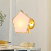 Modern brass finish pentagon wall lamp with gold-toned metal wall sconce and soft pink frosted glass shade for bedroom