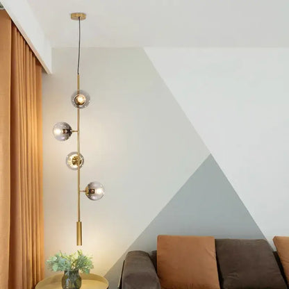 Modern brass five globe glass pendant lights with frosted globe shades for dining room featuring vertical suspension