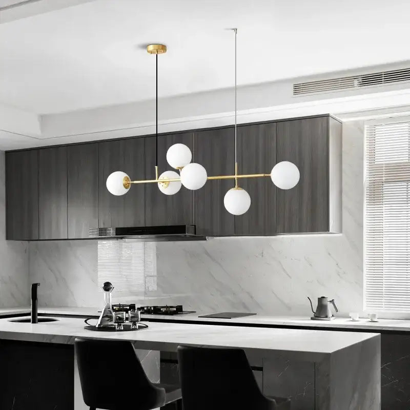 Modern pendant light with a golden glass ball design featuring five white spherical shades and a brass frame