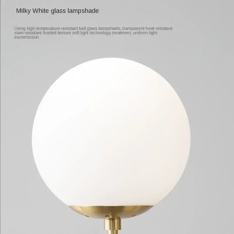 Modern brass pendant light featuring a milky white spherical golden glass ball lampshade with a brass base