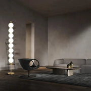 Modern brass floor lamp with six glowing white spherical bulbs on a slender gold-toned brass floor lamp stand for decorbites