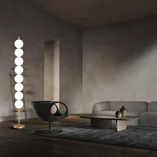 Modern brass floor lamp with six glowing white spherical bulbs on a slender gold-toned brass floor lamp stand for decorbites