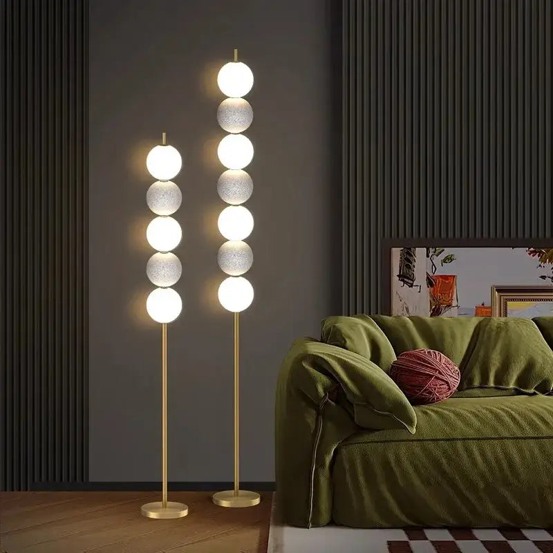 Modern brass floor lamp with six glowing brass spheres and slender gold-toned stand for living room decor by decorbites